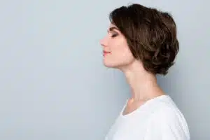 Side profile of a content woman showcasing results of rhinoplasty for facial symmetry.