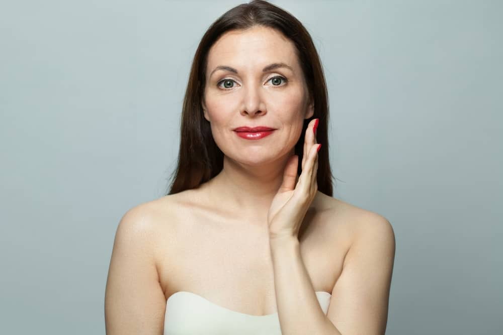 A woman highlighting her smooth jawline and neck after a surgical facelift, showcasing the balance and restraint of modern facial anatomy techniques.