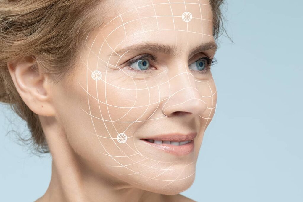 A digital anatomical overlay on a woman’s face showing a grid and target points used by a facial plastic surgeon to plan precise facelift incision placement.
