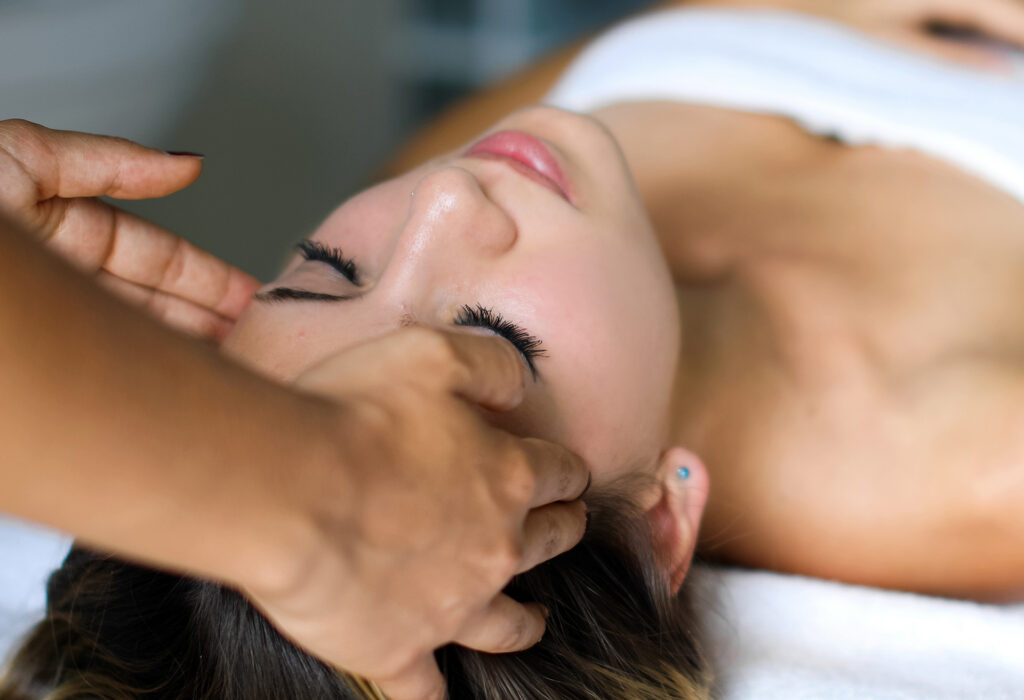 Patient receiving manual lymphatic drainage facial massage to reduce swelling and support post-surgical healing