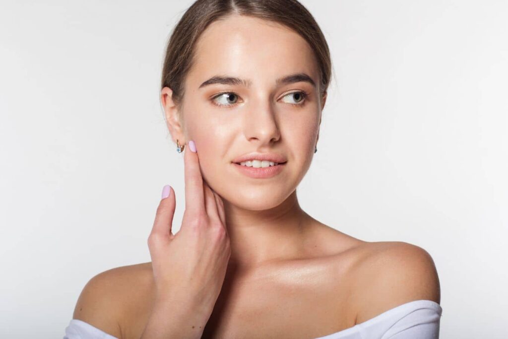 Woman touching smooth facial skin, highlighting microdermabrasion for acne scars and improved texture.