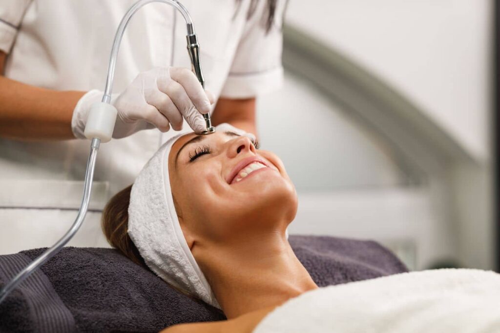 Esthetician performing microdermabrasion treatment to improve acne scars and skin texture